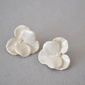 Macro view of floral stud earrings with pearly enamel petals and gold zircon center