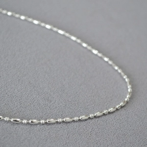 Macro shot of minimalist polished brass barrel chain link with mirror finish