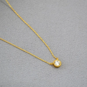 Detailed close-up of a round cubic zirconia pendant with a vintage gold beaded edge