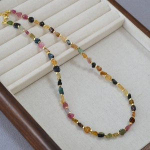 Detailed view of colorful irregular tourmaline beads with gold spacers on a jewelry tray
