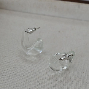 Close-up of minimalist clear glass C-shaped drop earrings with silver butterfly backings