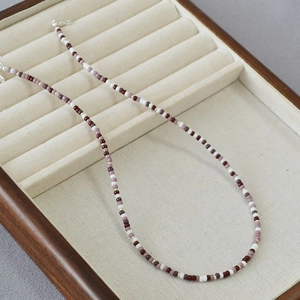 Detail of Miyuki bead necklace with burgundy seed beads and silver clasp on a tray