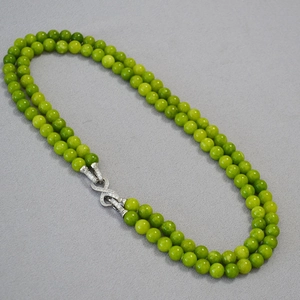 Macro view of double-layer green jade beaded necklace with silver infinity clasp