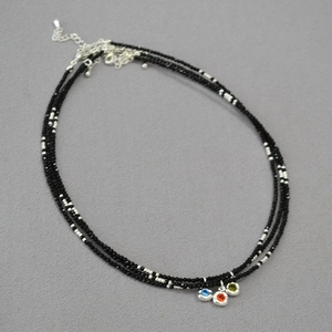 Detailed view of triple-layered black beaded necklace with three colorful gemstone charms