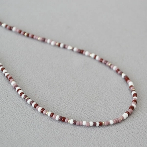 Close-up of red and gold Miyuki seed beads on an elegant Bohemian necklace strand