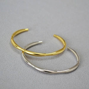 Detail view of gold and silver minimalist open bangles with high-polished metallic finish