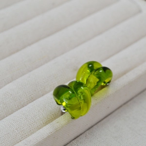Close-up of grass green translucent teardrop glass studs on a textured jewelry tray