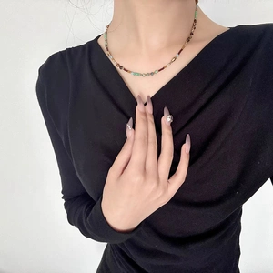 Détail du collier de perles Miyuki colorées porté par un mannequin sur fond noir et blanc