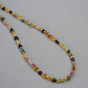 Detailed close-up of colorful irregular tourmaline beads with gold spacer accents