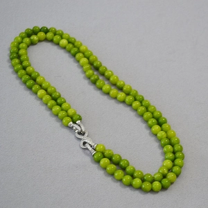 Detail of double-layer green jade bead necklace with sparkling infinity metal clasp