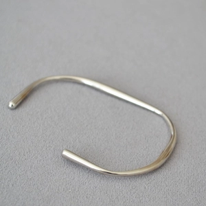 Nahaufnahme eines minimalistischen Armreifs in Silberoptik mit glatten runden Enden