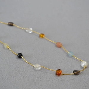 Handmade necklace with natural stones pearls and gold metal beads on gray fabric