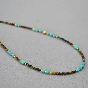 Macro view of bohemian beaded necklace with turquoise stones and golden accents