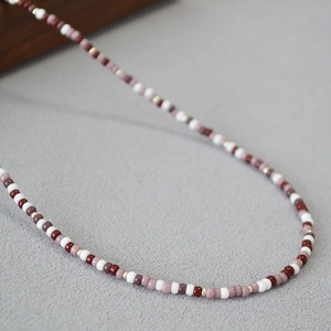 Detailed shot of bohemian beaded necklace with red and white beads and gold accents
