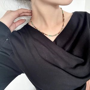 Détail d'un collier de perles multicolores avec accents dorés porté par un mannequin