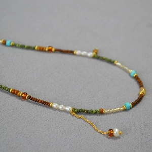 Détail du collier artisanal bohème avec perles turquoise, blanches et détails de chaîne dorée