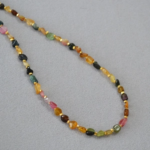 Macro detail of irregular tourmaline beads with gold square spacers on a choker necklace