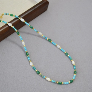 Detail of beaded necklace with blue turquoise, white stones, and gold metal beads