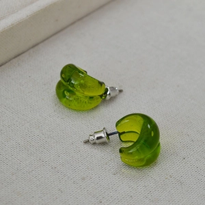 Detail of translucent grass green teardrop studs on rustic linen fabric with a gift box