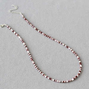 Detail of Miyuki bead necklace featuring red, purple, and white beads with lobster clasp