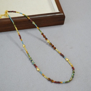 Détail d'un collier de perles colorées avec pierres œil de tigre et fermoir doré