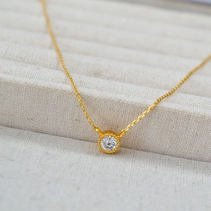 Macro detail of gold-plated brass necklace featuring a bezel-set round cubic zirconia