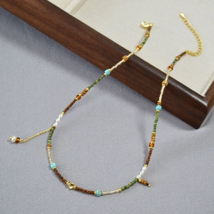 Détail d'un collier de perles coloré fait main avec chaîne dorée et perles turquoise