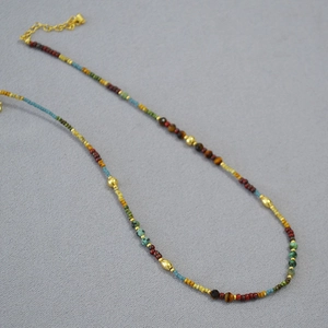 Détail d'un collier bohème en perles colorées avec accents dorés et chaîne réglable