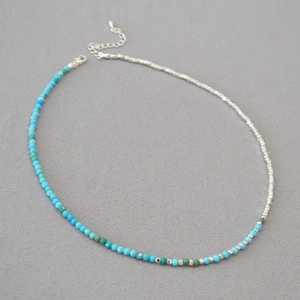 Detail of beaded necklace with blue and green beads, silver chain, and lobster clasp