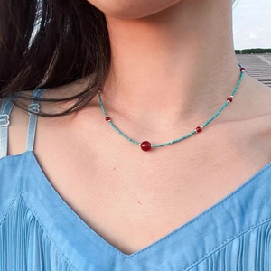 Minimalist turquoise and red agate beaded necklace with gold spacers on a female model