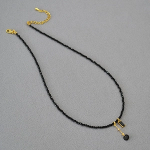 Détail du collier de perles noires avec pendentifs carrés et ronds et fermoir doré brillant