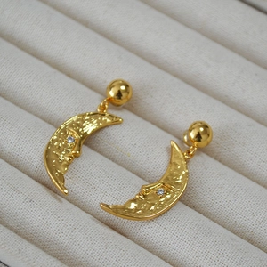 Detail of vintage moon face earrings with hammered texture and small zircon stone