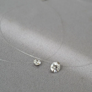 Détail macro du pendentif double pierre en zircone étincelant sur fil de pêche invisible