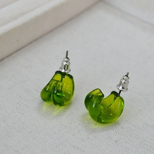 Close-up of green translucent teardrop glass earrings on a white linen texture tray