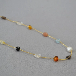 Macro view of thin gold beaded chain necklace with colorful irregular natural stones