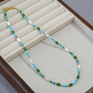 Elegant beaded necklace with blue turquoise and white shell pearls on beige velvet