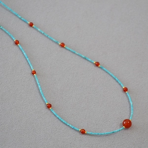 Detail view of turquoise seed beads and red agate necklace with gold metal spacers