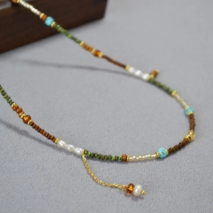 Détail macro d'un collier de perles fait main avec turquoise, perles et chaîne d'extension dorée
