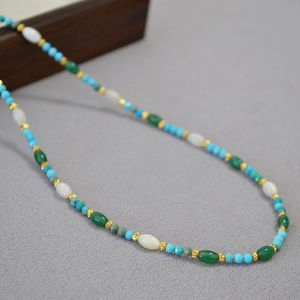 Detail of beaded necklace with blue turquoise, white shell, and gold accent beads