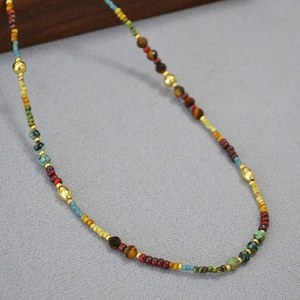 Détail d'un collier bohème en perles colorées avec accents dorés et pierres naturelles