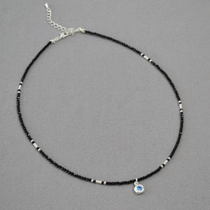 Detailed macro view of black bead necklace with blue gemstone pendant and lobster clasp