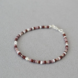 Detail of bohemian red and white bead necklace with gold spacers and metal lobster clasp