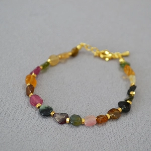 Detailed macro view of colorful irregular tourmaline beads and golden metal spacers