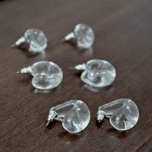 Macro detail of transparent waterdrop heart-shaped glass earrings on wood background