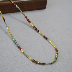 Détail d'un collier de perles colorées avec turquoise et oeil de tigre sur bois