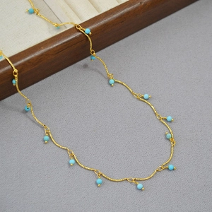 Macro detail of gold plated brass chain necklace featuring turquoise faceted beads
