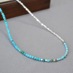 Detail of silver beads and green turquoise faceted stones on a minimalist thin necklace
