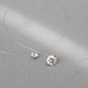 Vue macro d'un collier fil invisible avec deux oxydes de zirconium blancs scintillants