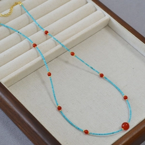 Close-up of turquoise and red agate beaded necklace with gold spacer beads and clasp