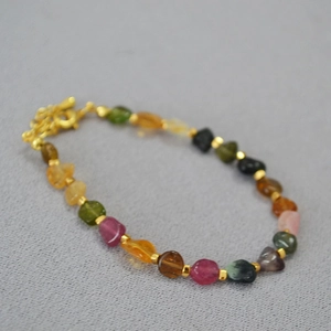 Detailed macro view of multi-colored irregular gemstone beads with gold spacers and clasp